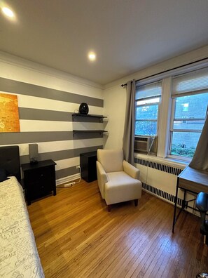 A bedroom with a bed, a chair, a desk, a radiator, and a window with a view of the outside. - Two Large Cozy Bedroom Condominium that is 20 mins train ride to Manhattan
 (Queens)