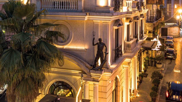 A historic building with a classical facade, large windows, and a statue on the balcony. - Envy Hotel (Durrës)