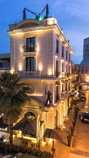A historic building with a classical facade, large windows, and a statue on the balcony. - Envy Hotel (Durrës)