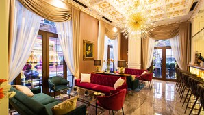 A luxurious hotel lobby with a red sofa, green armchairs, a glass coffee table, and a chandelier. - Envy Hotel (Durrës)