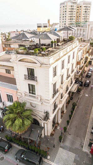 A multi-story building with balconies, outdoor seating, and a palm tree. - Envy Hotel (Durrës)