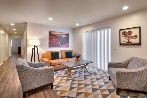 A modern living room with a sofa, two armchairs, a coffee table, and a painting on the wall. - 2G New Moab RedCliff Condo, Pool & Hot Tub (Moab)