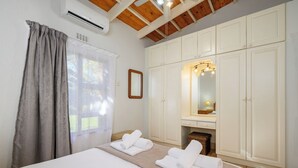 A bedroom with a bed, a mirror, a wardrobe, and a window with curtains. - San Lameer Villa 2018 (Southbroom)