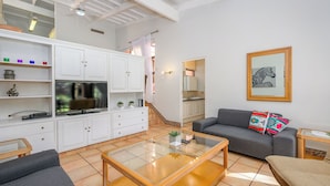 A modern living room with a sofa, coffee table, and TV. There is a staircase leading to a kitchen. - San Lameer Villa 2018 (Southbroom)