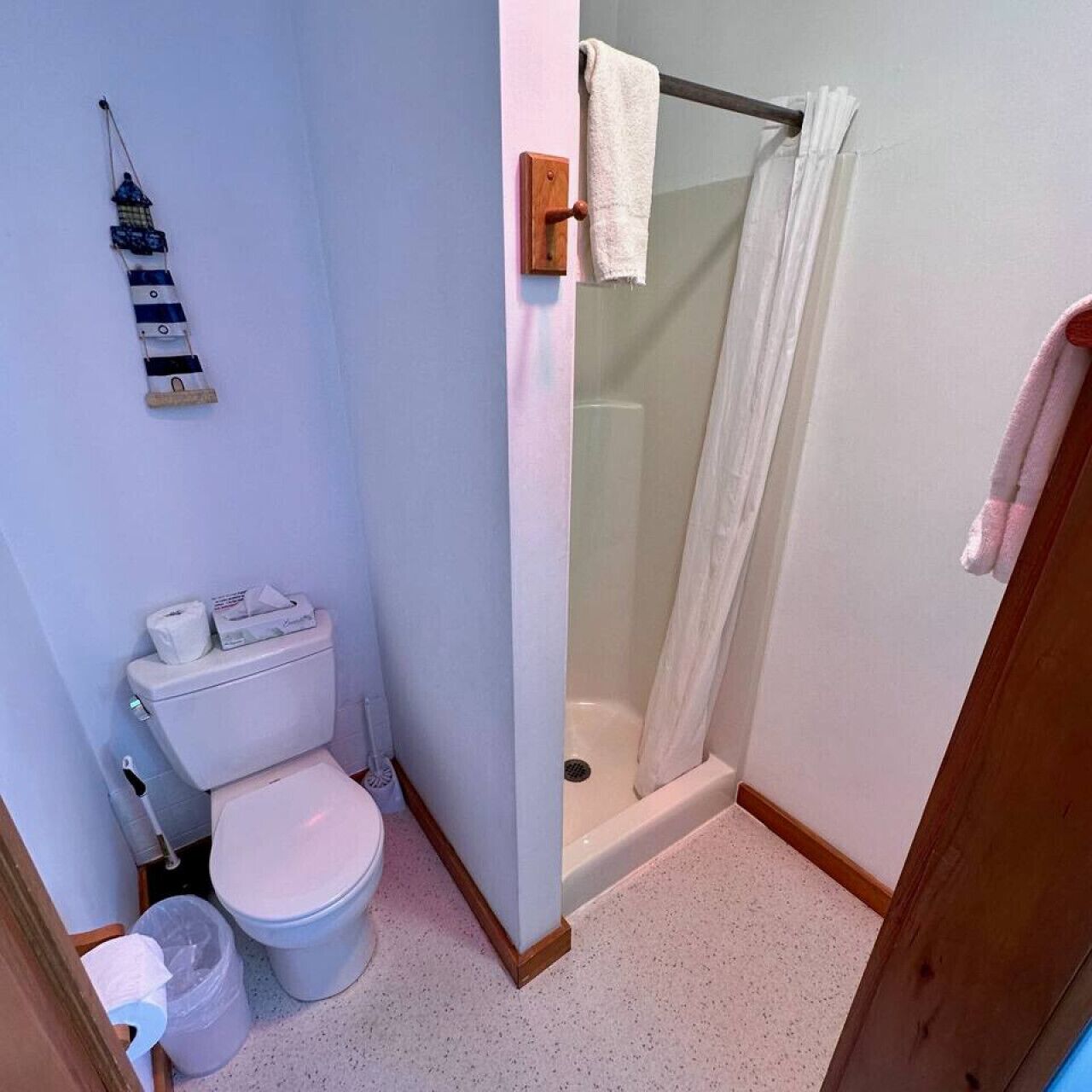 Une petite salle de bain comprenant des toilettes, une douche et un porte-serviettes.