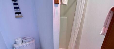 Une petite salle de bain comprenant des toilettes, une douche et un porte-serviettes.