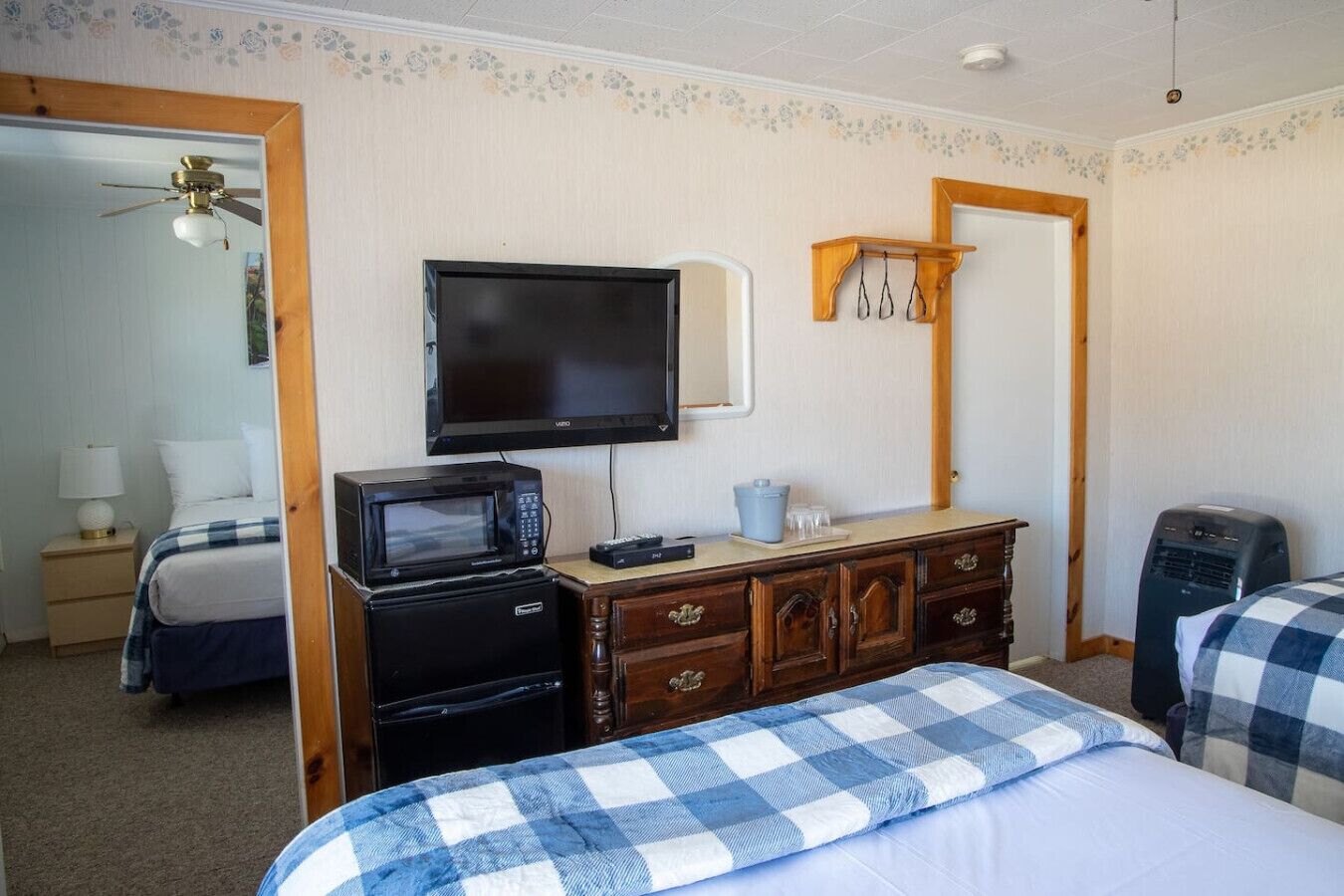 Ein Hotelzimmer mit einem Bett, einem Schminktisch, einer Mikrowelle, einem Fernseher und einem Heizgerät.