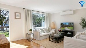 A modern living room with a sofa, coffee table, and TV. - Bluebird Cottage – cheerful and cosy home, short distance to Bowral (Bowral)
