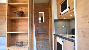A wooden interior with a kitchen area, including a microwave, sink, and cabinets. - Cozy studio near slopes - 4 guests (Méribel)
