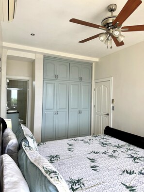 Une chambre à coucher avec un lit, une armoire, un ventilateur de plafond et une porte.
