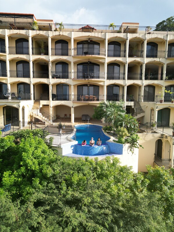 Un hotel a più piani con una piscina centrale circondata da vegetazione lussureggiante.