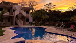 A swimming pool with a modern architectural building in the background. - Charming condo with a rooftop, across beach (Playas Del Coco)