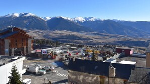 A town with a mountain backdrop, featuring a building with a stone facade and a red roof. - Charming 2-room cabin in central Font-Romeu, parking included (Font-Romeu-Odeillo-Via)