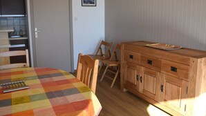 A room with a wooden cabinet, a table with a colorful tablecloth, and a chair. - Charming 2-room cabin in central Font-Romeu, parking included (Font-Romeu-Odeillo-Via)