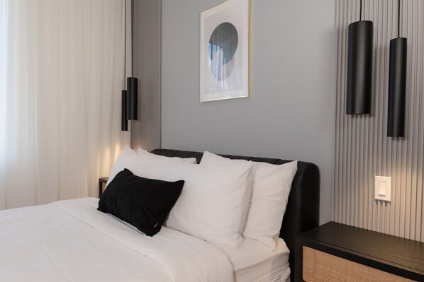 A hotel room with a bed, a nightstand, a wall-mounted light, and a framed picture.