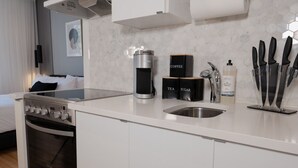 Een moderne keuken met een inbouwoven, een koffiezetapparaat, theezuiger en suikerpotten, en een messenblok.