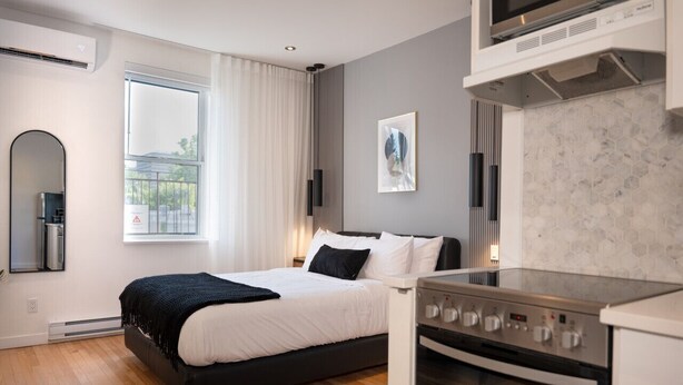Een moderne slaapkamer met een bed, een ingebouwde oven en een groot raam.