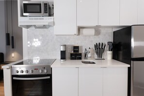 A modern kitchen with a microwave, coffee maker, tea and sugar dispensers, and a stainless steel refrigerator.