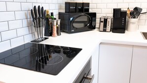 A modern kitchen with a black microwave, a toaster, and a coffee maker. There are spice containers and a knife holder on the counter. - #9 - Studio/Plateau/St-Denis/SelfCheck-In/AC/TV (Montréal)