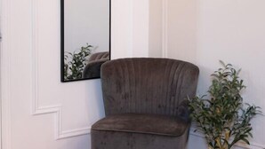A room with a grey upholstered chair, a large mirror, and a small potted plant. - #9 - Studio/Plateau/St-Denis/SelfCheck-In/AC/TV (Montréal)
