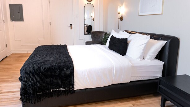 A bedroom with a bed, bedside table, wall-mounted lights, a mirror, and a door. - #9 - Studio/Plateau/St-Denis/SelfCheck-In/AC/TV (Montréal)