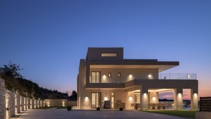 A modern two-story house with a flat roof, large windows, and a balcony. - Casa Beleza Villa, a Mythical Retreat (Perama)