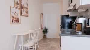 A modern kitchen with a coffee machine, a white table with chairs, and framed pictures on the wall. - #10 - Studio/Plateau/St-Denis/SelfCheck-In/AC/TV (Montréal)