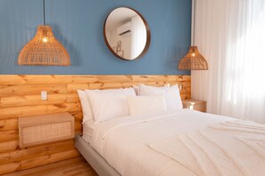 Ein Schlafzimmer mit einem Holzkopfteil, einem runden Spiegel, zwei Pendelleuchten und einem Nachttisch.
