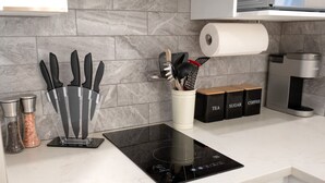 A kitchen with a black induction cooktop, a knife block, a spice rack, and a coffee machine. - #2 - Studio/Plateau/St-Denis/SelfCheck-In/AC/TV (Montréal)
