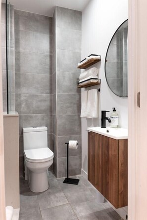 A bathroom with a toilet, a sink with a mirror, and a towel rack. - #2 - Studio/Plateau/St-Denis/SelfCheck-In/AC/TV (Montréal)