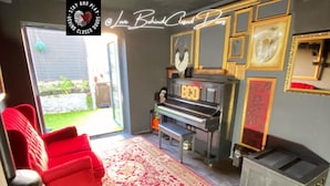 A living room with a piano, red chairs, a large rug, and a fireplace. - Stay & Play at Lovebehindcloseddoors (Plymouth)