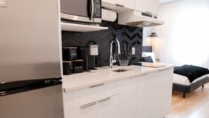 A modern kitchen with a microwave, coffee maker, and kettle on the countertop.