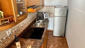 Eine kleine Küche mit Holzausstattung, einem Backofen, einer Spüle und einem Kühlschrank.