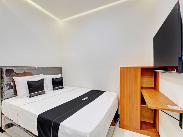A modern hotel room with a neatly made bed, a wooden nightstand, and a flat-screen TV mounted on the wall.