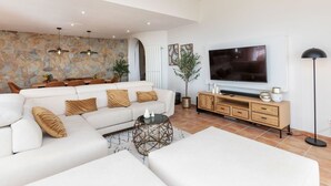Un salon moderne avec un canapé d’angle, un téléviseur et un mur en pierre.