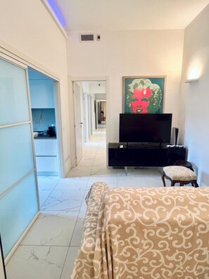 Une chambre d’hôtel avec un lit, une télévision, un tableau et une armoire.