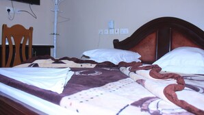 Una cama con cabecera marrón, almohadas blancas y una colcha estampada.