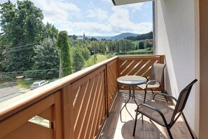 Un balcon avec une balustrade en bois, une petite table ronde et deux chaises.