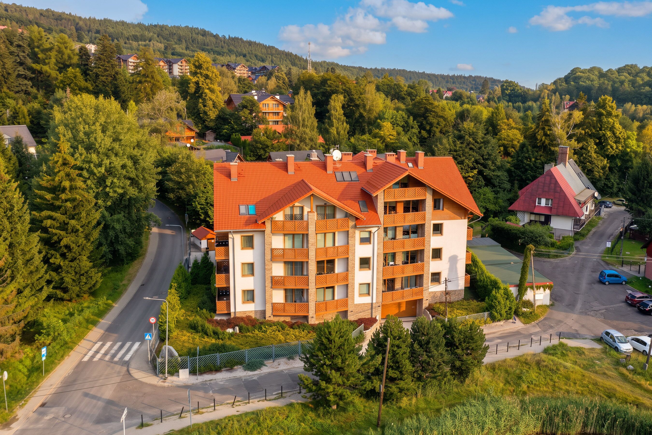 A multi-story hotel with a red-tiled roof, surrounded by lush greenery and a hilly landscape.
