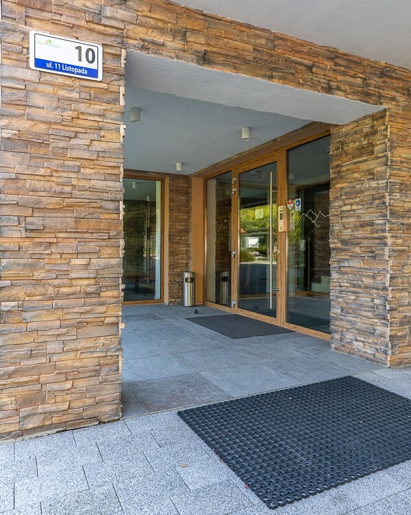 A stone facade with a sign indicating '10' and 'ul. 11 Listopada'. - RentPlanet - Apartamenty Bawaria (Szklarska Poreba)