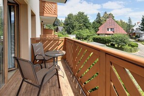 Un balcon avec une balustrade en bois, une table et deux chaises.