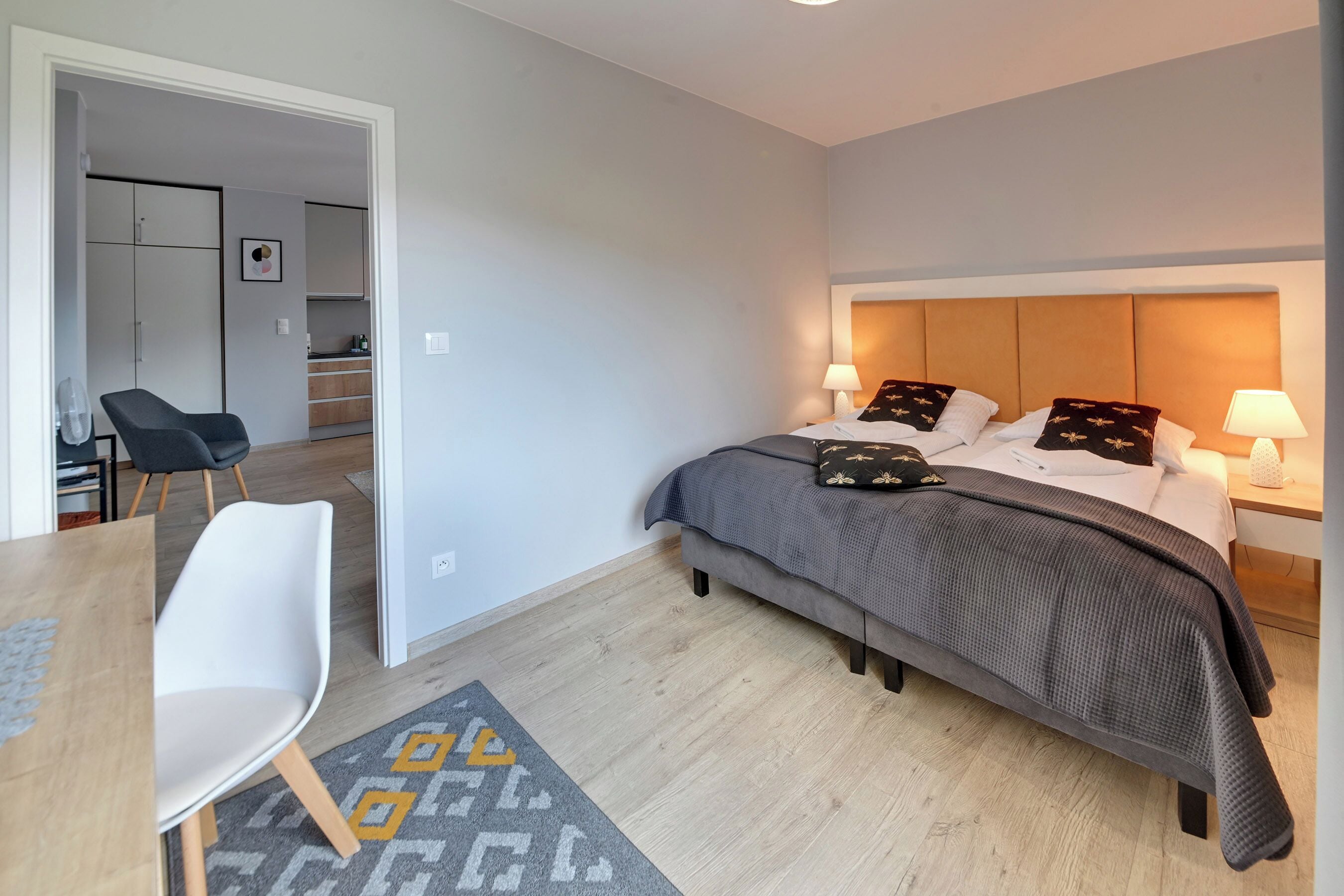 Et moderne hotelværelse med seng, sengeborde, et skrivebord og en stol.