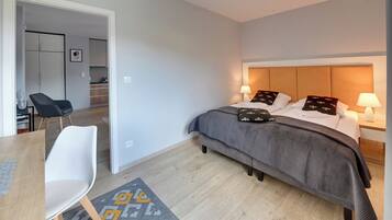 Et moderne hotelværelse med seng, sengeborde, et skrivebord og en stol.