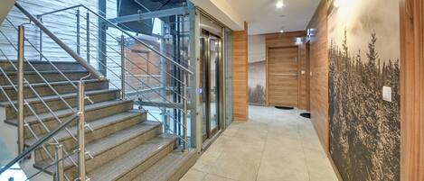 A modern interior with a staircase, glass doors, and a mural.