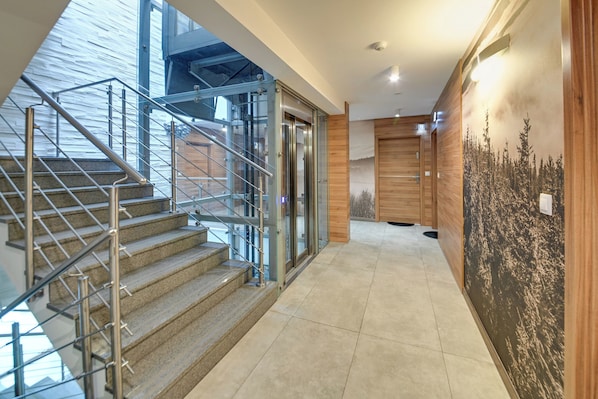 A modern interior with a staircase, glass doors, and a mural.