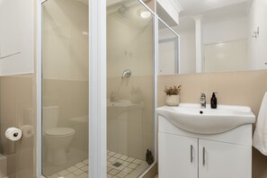 A modern bathroom with a glass-enclosed shower, a white sink, and a toilet. - Azure 32 (Cape Town)