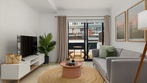 A modern living room with a flat-screen TV, a grey sofa, a round coffee table, and a large window with curtains. - Azure 32 (Cape Town)