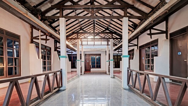 A covered corridor with tiled flooring, wooden railings, and columns. - SPOT ON 92983 Hotel Ayu (Semarang)