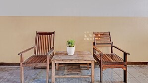 A wooden table with two chairs and a potted plant in the center. - SPOT ON 92983 Hotel Ayu (Semarang)