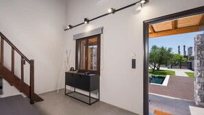 Een modern interieur met een trap, een zwarte console tafel en uitzicht naar buiten.